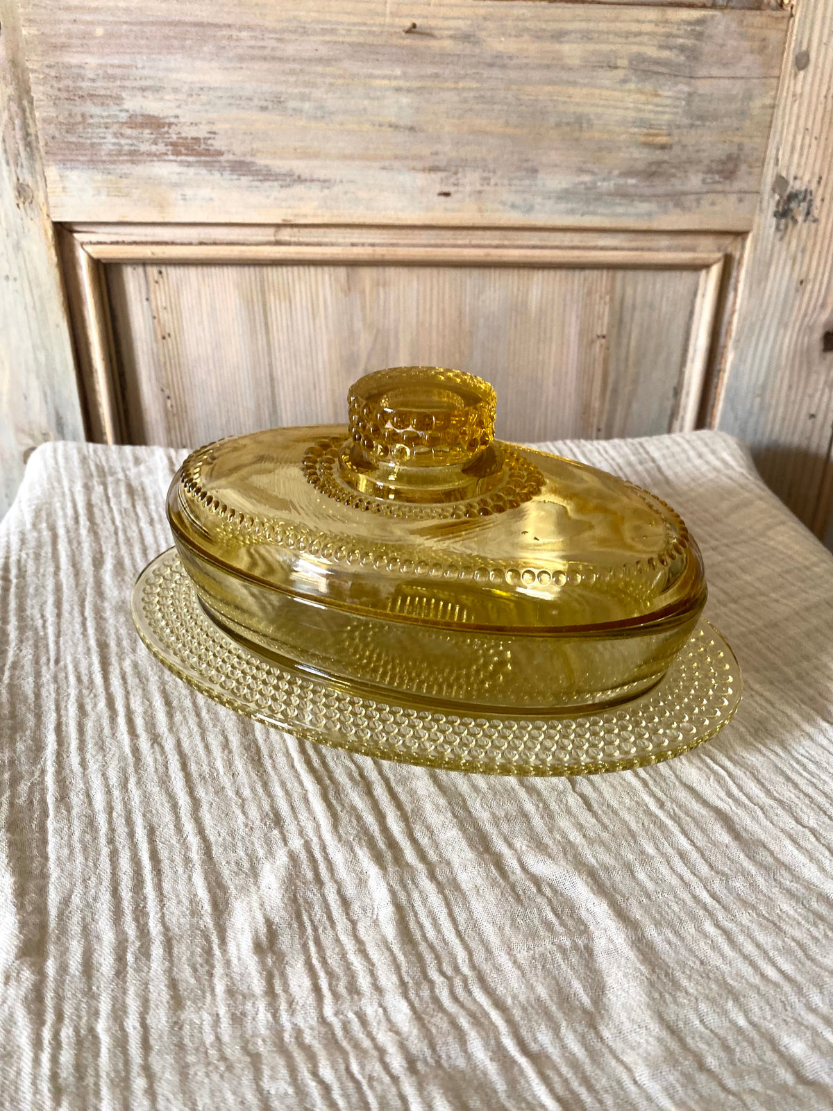 Beurrier ovale en verre ambré moulé, décor perlé - 1960
